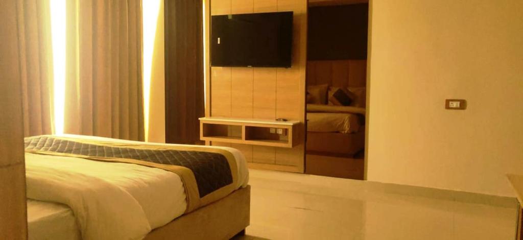 a bedroom with a bed and a flat screen tv at Hotel Sakura by Maps in Gurgaon