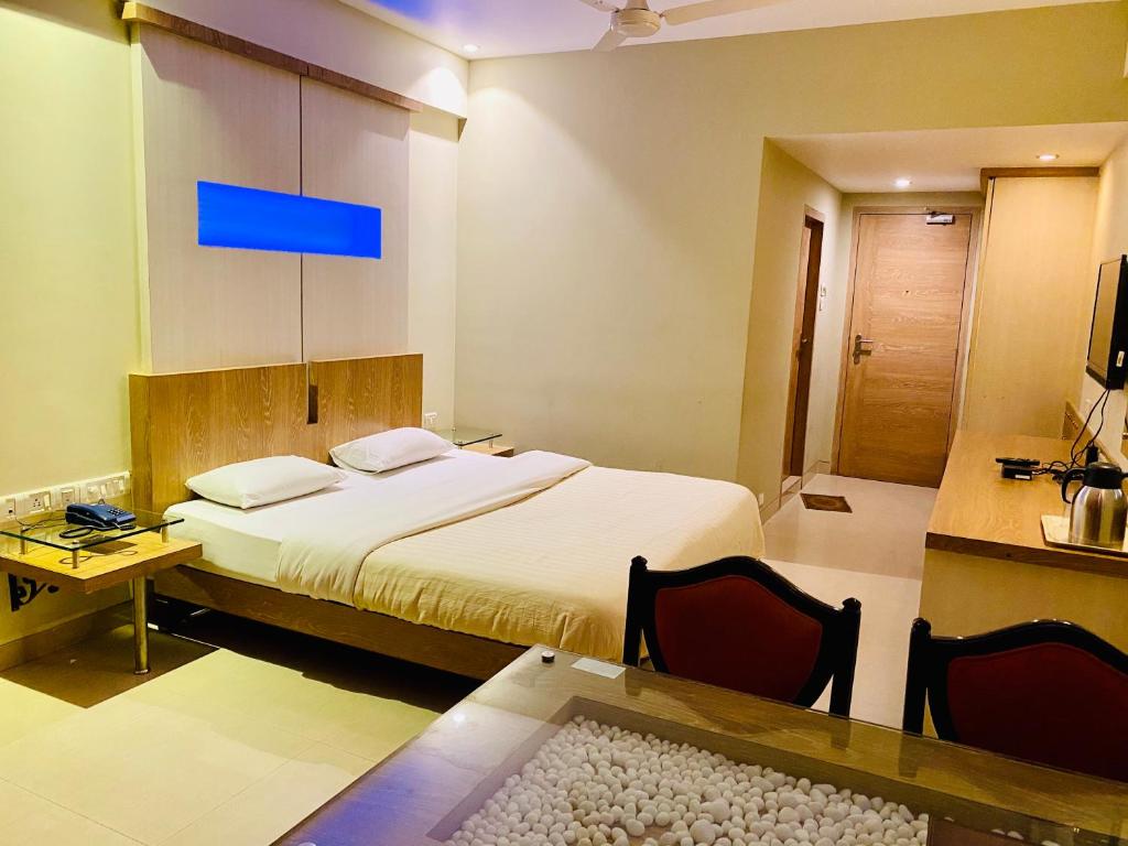1 dormitorio con 1 cama y 1 mesa con sillas en Hotel Rama Krishna en Lonavala