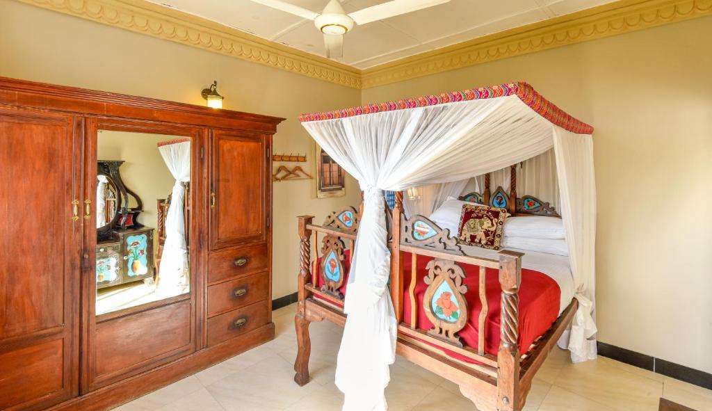 a bedroom with a canopy bed and wooden cabinets at Freddie Mercury Apartments in Zanzibar City