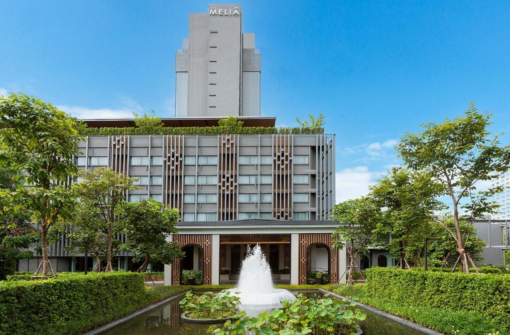 una fuente frente a un edificio con una torre en Melia Chiang Mai en Chiang Mai