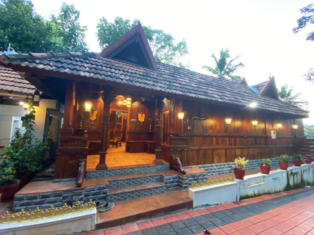 a home with a wooden fence and a porch at Mayoorapanjaram in Neyyāttinkara