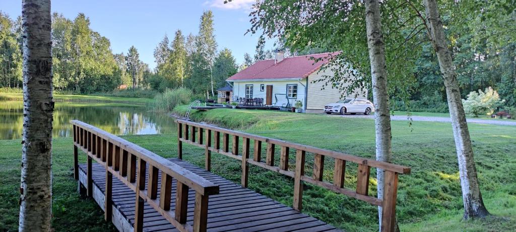 a wooden bridge leading to a house and a lake at Ninnujärve Private Holiday Home in Nasva