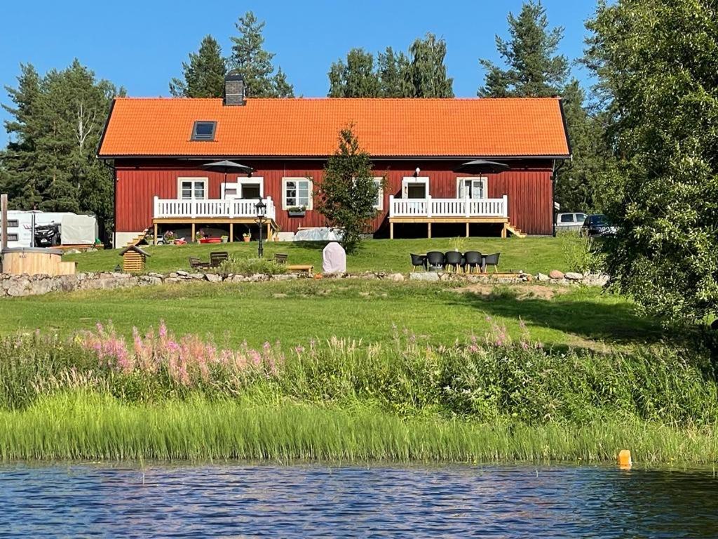 a red barn with an orange roof next to the water at Projekt Schwedenalm in Furudal