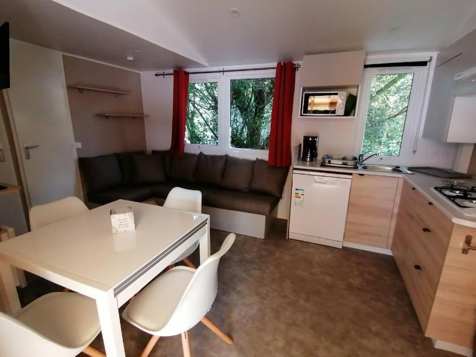 a kitchen and a living room with a table and chairs at MOBIL-HOME NEUF 6 PERSONNES réservation du samedi au samedi en juillet et août in Urt