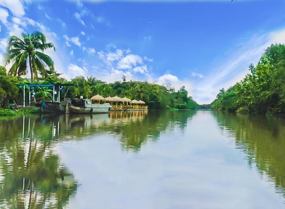 une rivière avec des bateaux et un palmier dans l'établissement Bamboo Eco Village, à Cần Thơ