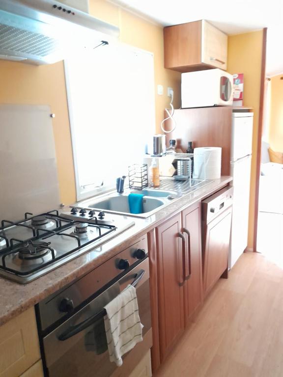 uma cozinha com um fogão e um lavatório em Mobil home camping les écureuils em Mimizan