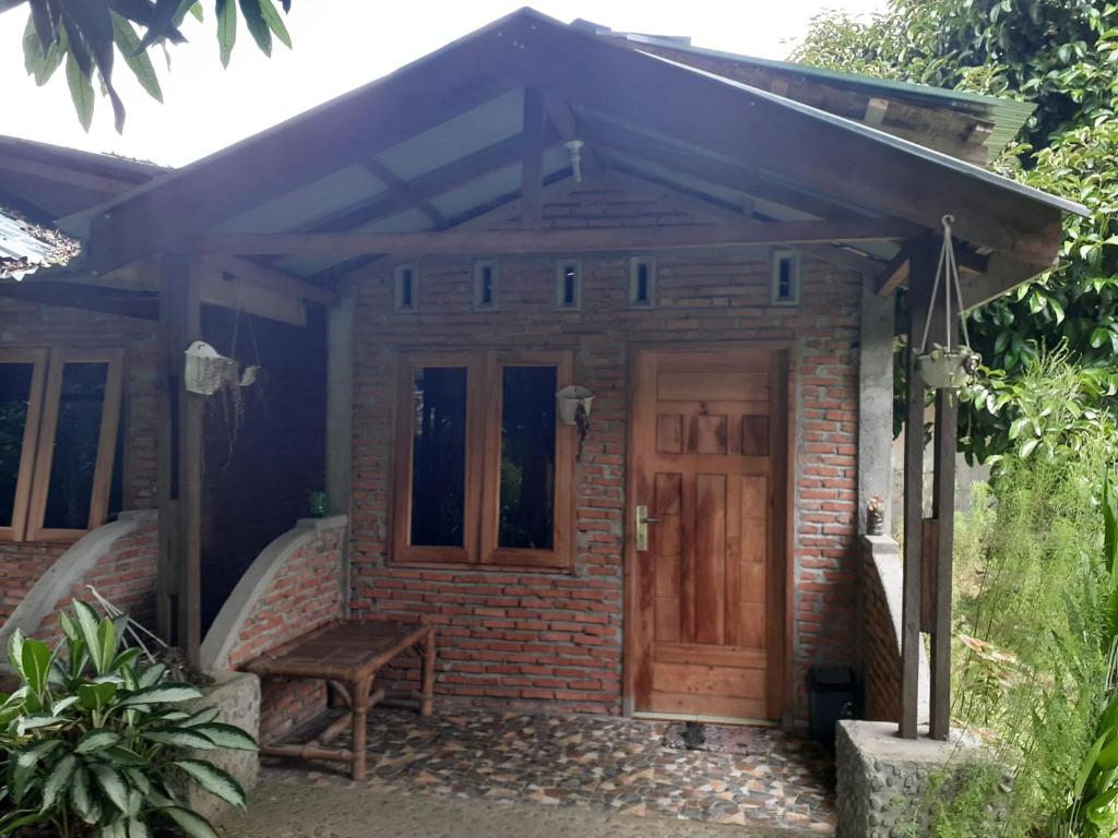 une maison en briques avec une porte en bois et un banc dans l'établissement Jhony's Backpacker-Guest House, à Bukit Lawang