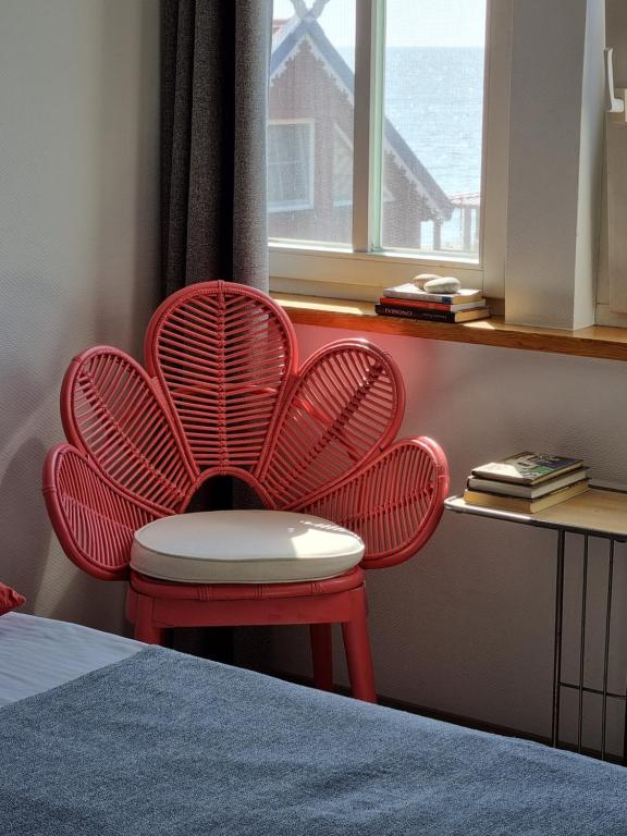 a red chair sitting next to a desk with a window at Marių vėjas in Nida