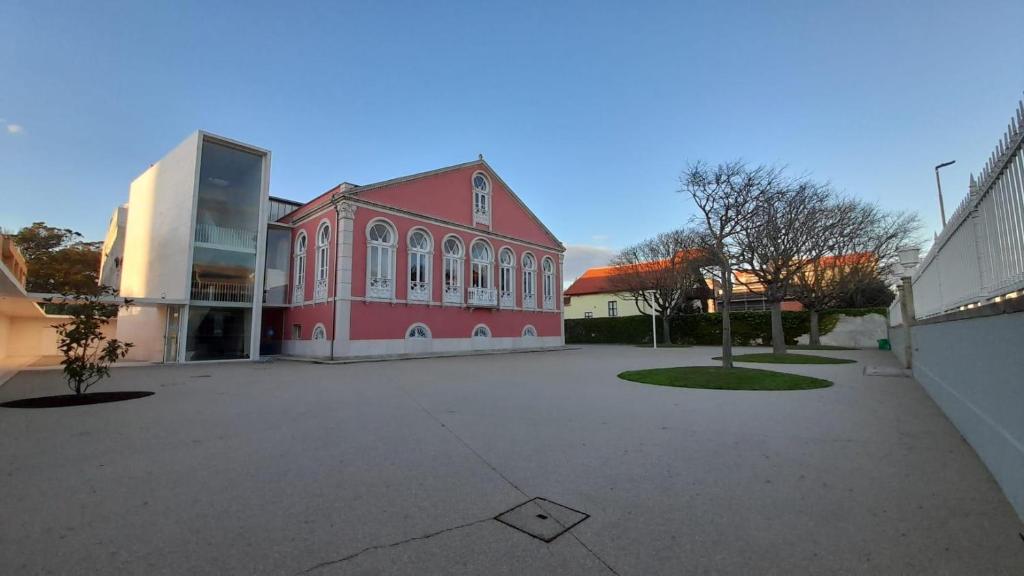 a large red building in a parking lot at HI Vila do Conde - Pousada de Juventude in Vila do Conde