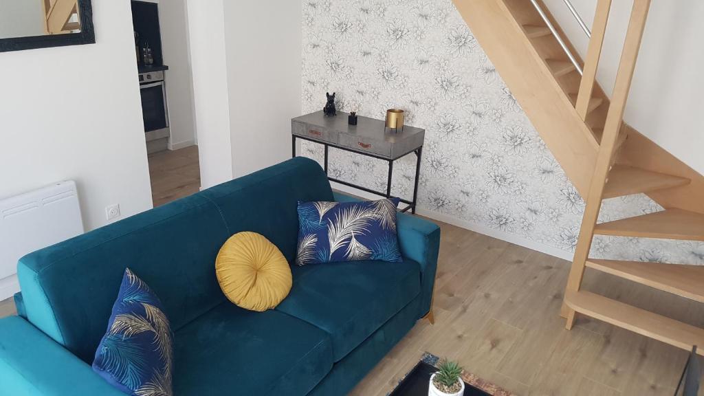 a blue couch with pillows in a living room at l'Aurore Dorée, duplex rénové - parking privé - wifi gratuit in Saint-Quentin
