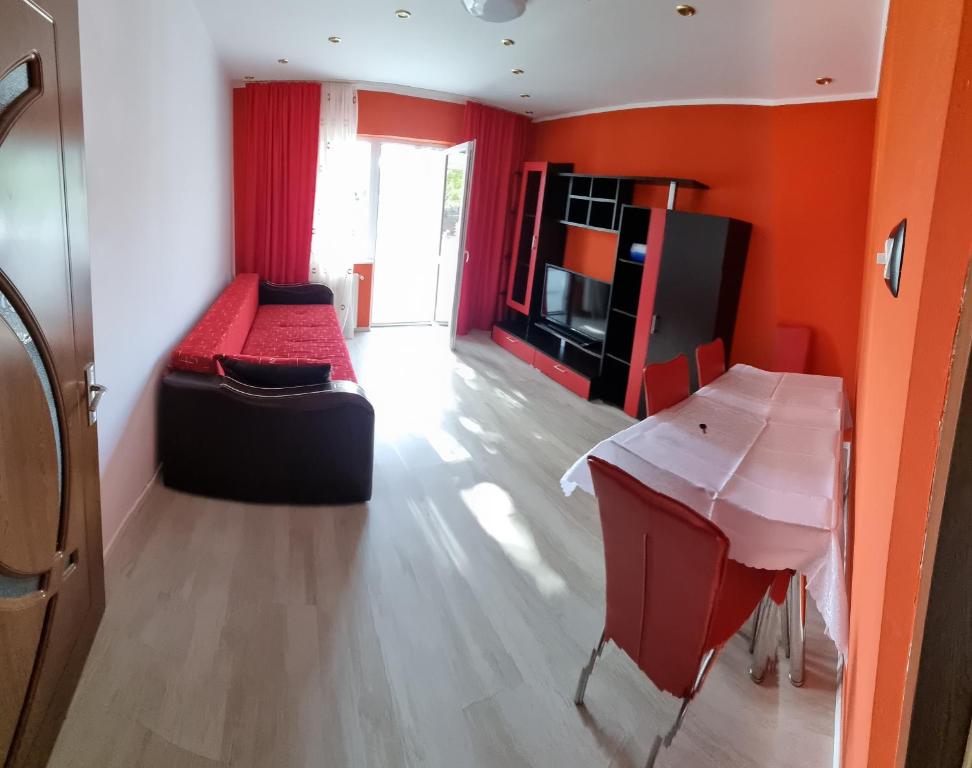 salon z pomarańczowymi ścianami, kanapą i stołem w obiekcie Apartament Mia w mieście Ocnele Mari