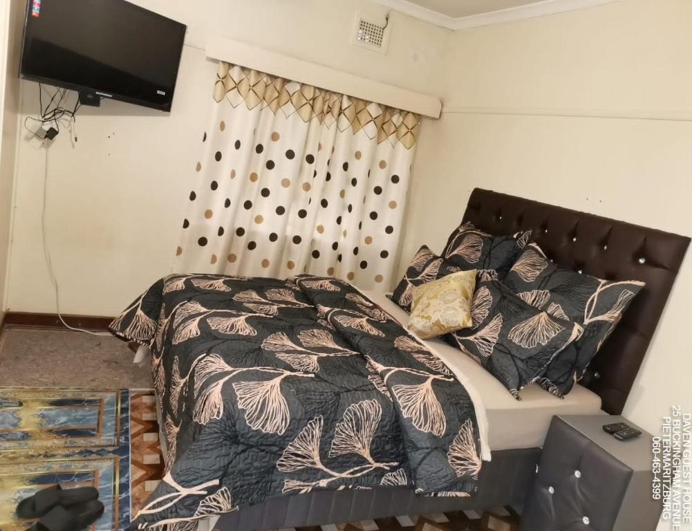a bedroom with a bed with a comforter and pillows at Daven Guest House in Pietermaritzburg