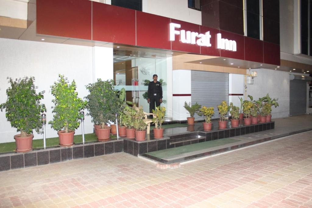 um homem parado em frente a uma loja com vasos de plantas em Hotel The Furat Inn em Vapi