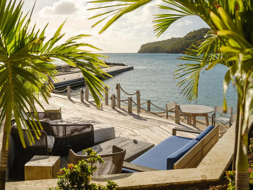 Blick auf das Meer von einem Resort mit Stühlen und Tischen in der Unterkunft The Liming Bequia in Friendship