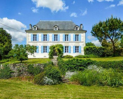 una gran casa blanca en la cima de un exuberante campo verde en Villa Mamba, en Saint-Porchaire