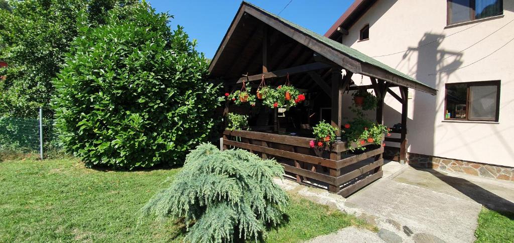 ein Haus mit einer hölzernen Veranda mit Blumen darauf in der Unterkunft Casa Lotrilor in Malaia