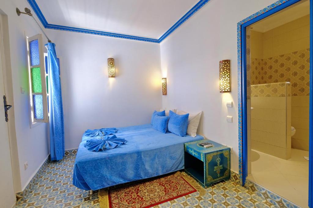 1 dormitorio con cama azul y ducha en Riad Hôtel Essaouira, en Marrakech