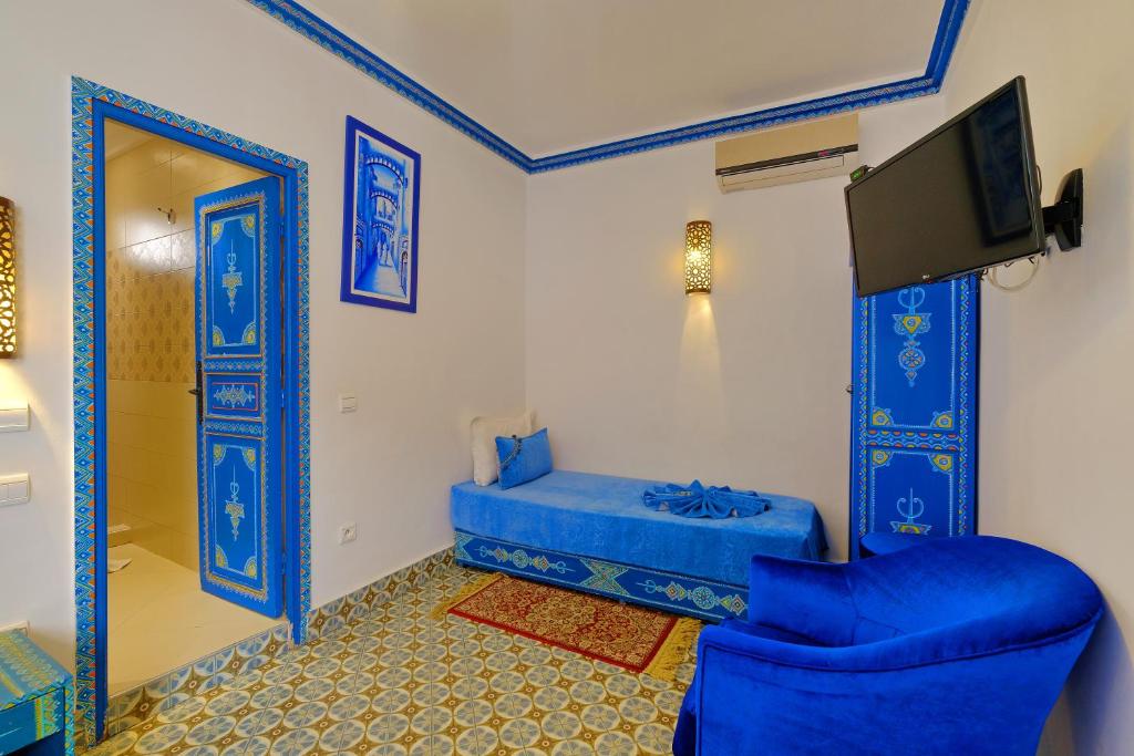 Una sala de estar con un sofá azul y un televisor. en Riad Hôtel Essaouira, en Marrakech