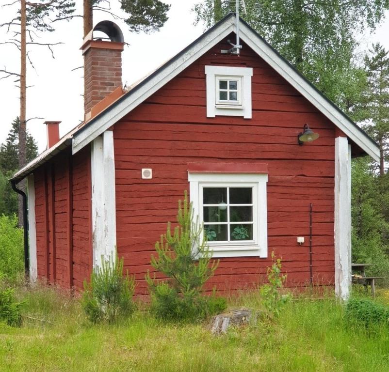 ein rotes Haus mit einem weißen Fenster und einem Kamin in der Unterkunft Cabin near lake and beautiful nature reserve. in Bodafors