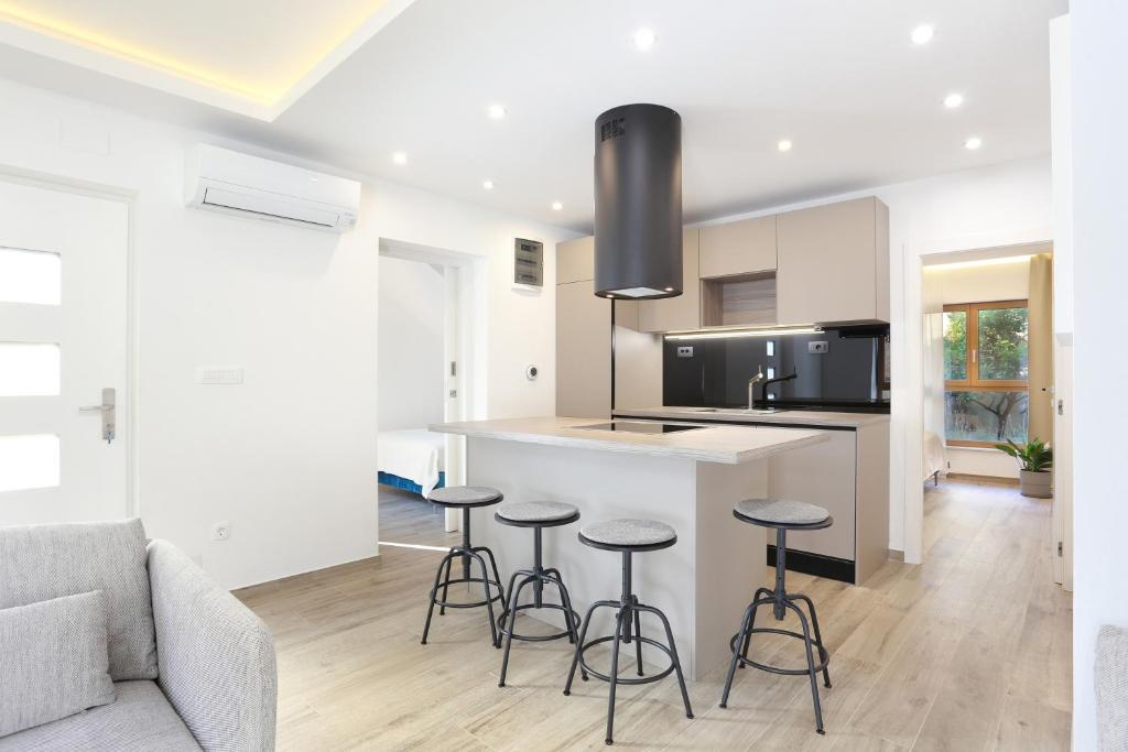 a kitchen and living room with a counter and stools at Apartments by the sea Podstrana, Split - 9714 in Podstrana