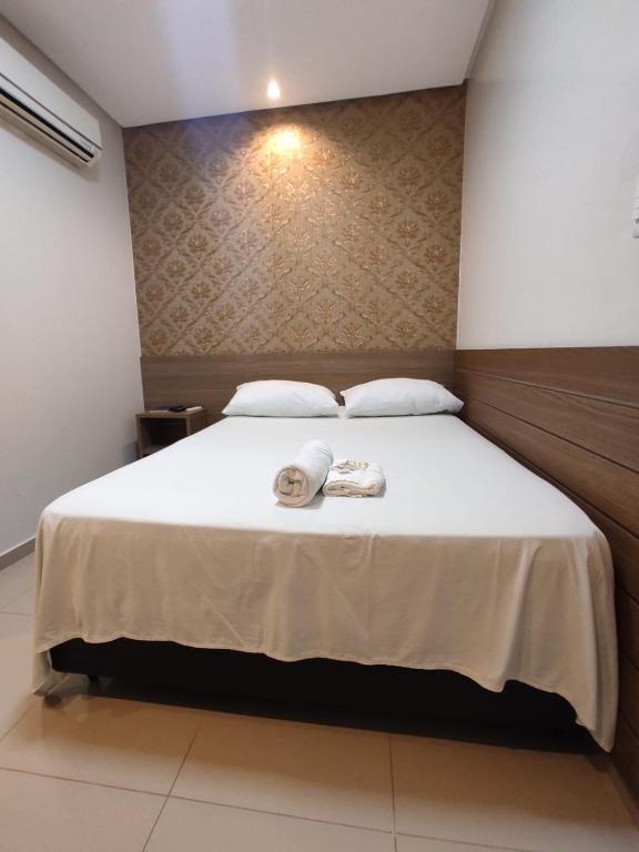 a bedroom with a bed with two towels on it at Hotel Universal in Santarém