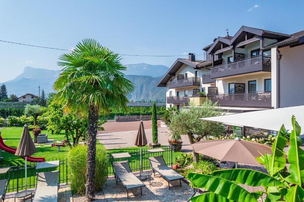 een resort met een palmboom en tafels en parasols bij Hotel Christine in Gargazzone