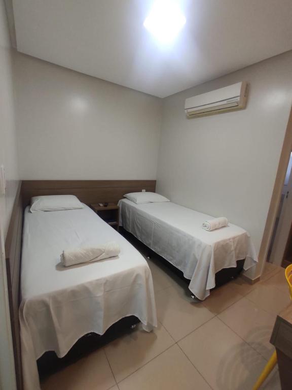 a room with two beds with white sheets at Hotel Universal in Santarém