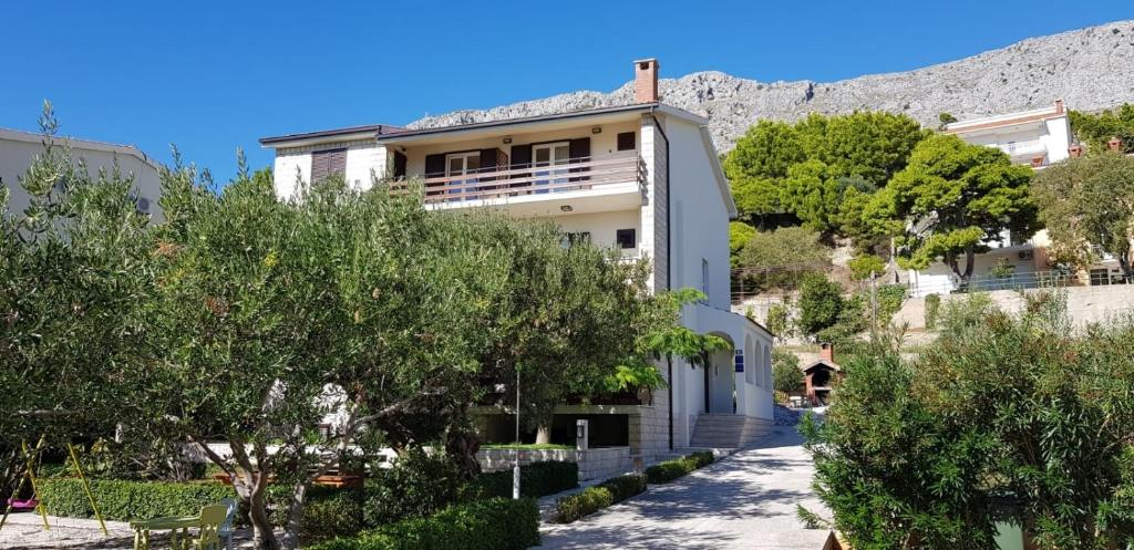 a white building with trees in front of a mountain at Apartment Duce 2821c in Duće