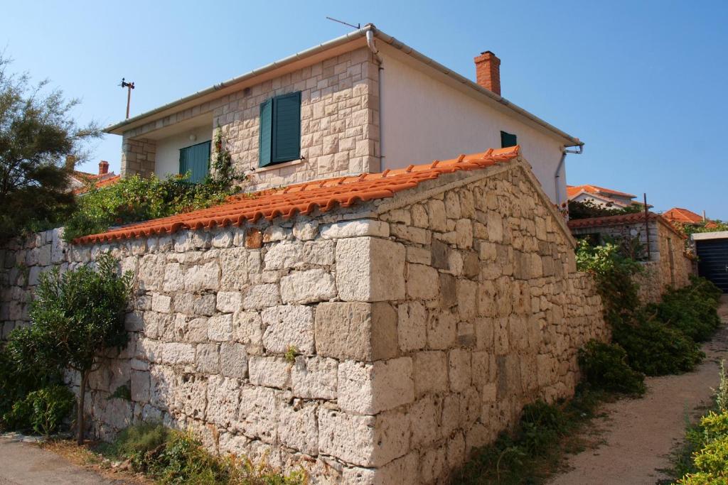 un mur en pierre avec une maison en arrière-plan dans l&#39;établissement Apartments by the sea Postira, Brac - 2888, à Postira