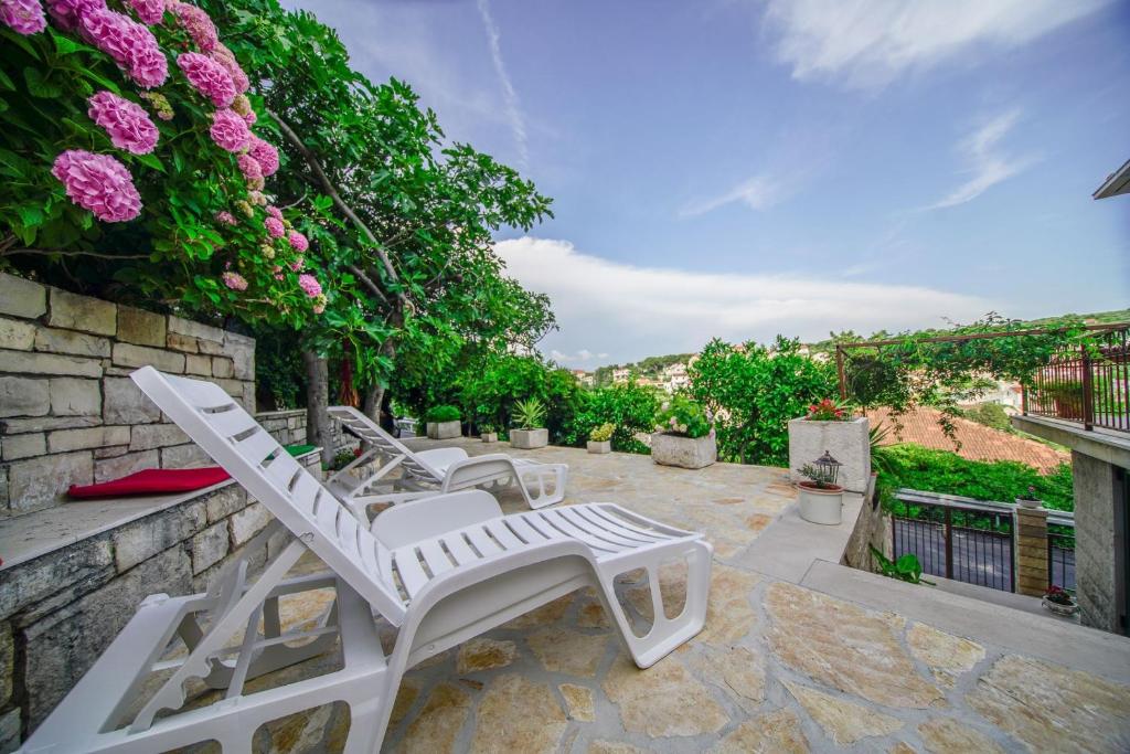 a pair of white chairs on a patio with flowers at Apartments with parking space Splitska, Brac - 2857 in Supetar