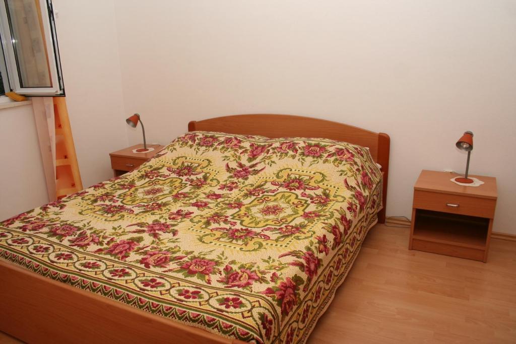 sypialnia z łóżkiem z kwiatowym kocem w obiekcie Apartment Bol 2884a w Bol