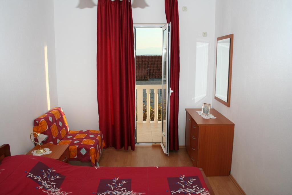 a living room with a chair and a window with red curtains at Apartment Bol 2884b in Bol
