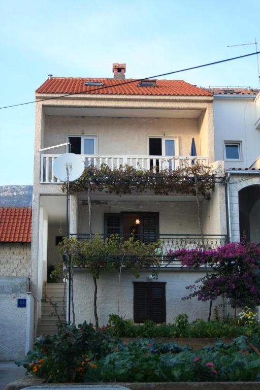 a white house with a balcony and flowers at Apartments with parking space Bol, Brac - 2884 in Bol