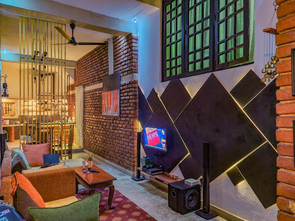 a living room with a brick wall with a tv at The Brick House Kandy in Kandy