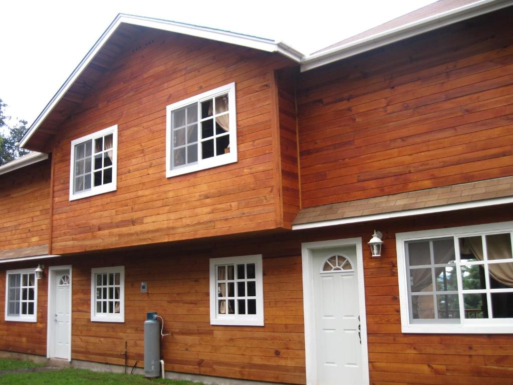 uma casa de madeira com janelas brancas e uma porta branca em Cabanas El Cerrito em Zirahuén