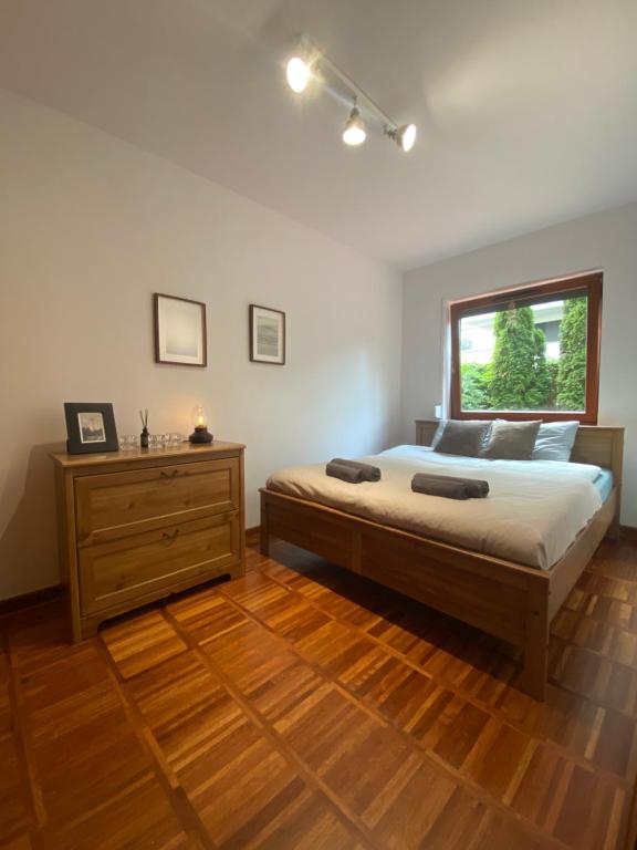 una camera con un letto, un comò in legno e una finestra di La Playa Apartament z ogródkiem a Hel
