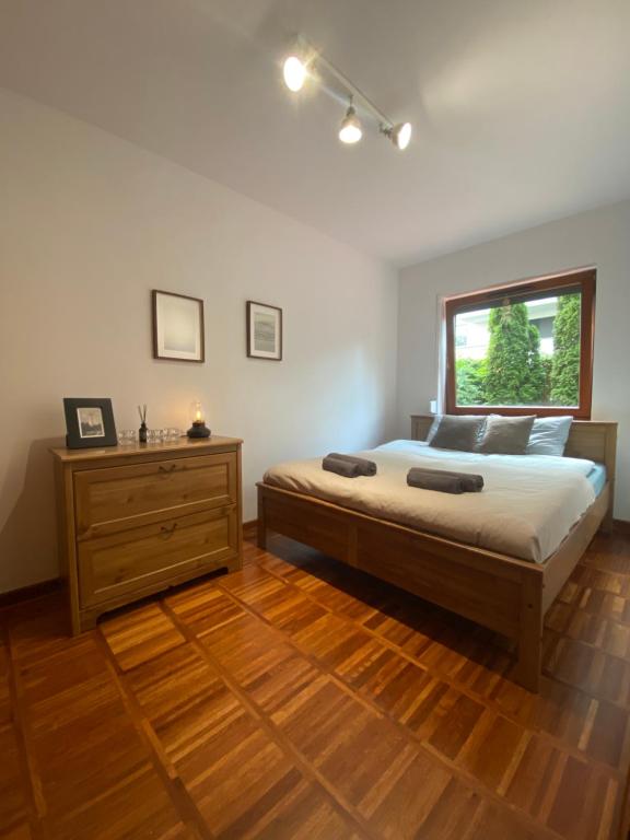 sypialnia z łóżkiem z drewnianą komodą i oknem w obiekcie La Playa Apartament z ogródkiem w mieście Hel