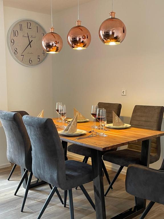 uma mesa de jantar com cadeiras e um relógio na parede em Ferienwohnung MaRe em Stockach