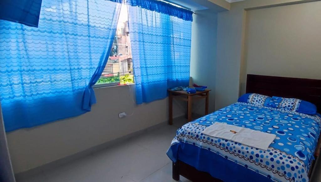 - une chambre bleue avec un lit et une fenêtre dans l'établissement HOSPEDAJE EL CANTARO II, à Tingo María