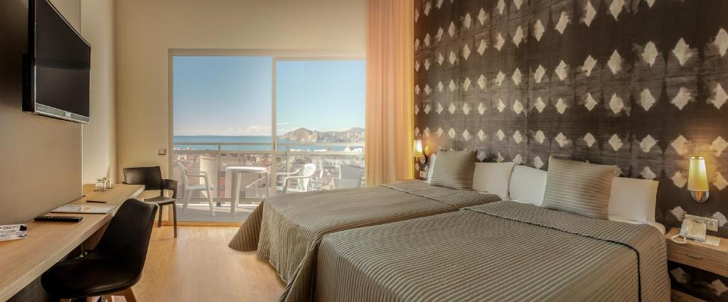 Schlafzimmer mit einem Bett, einem Schreibtisch und einem Fenster in der Unterkunft RH Princesa Hotel & Spa 4* Sup in Benidorm