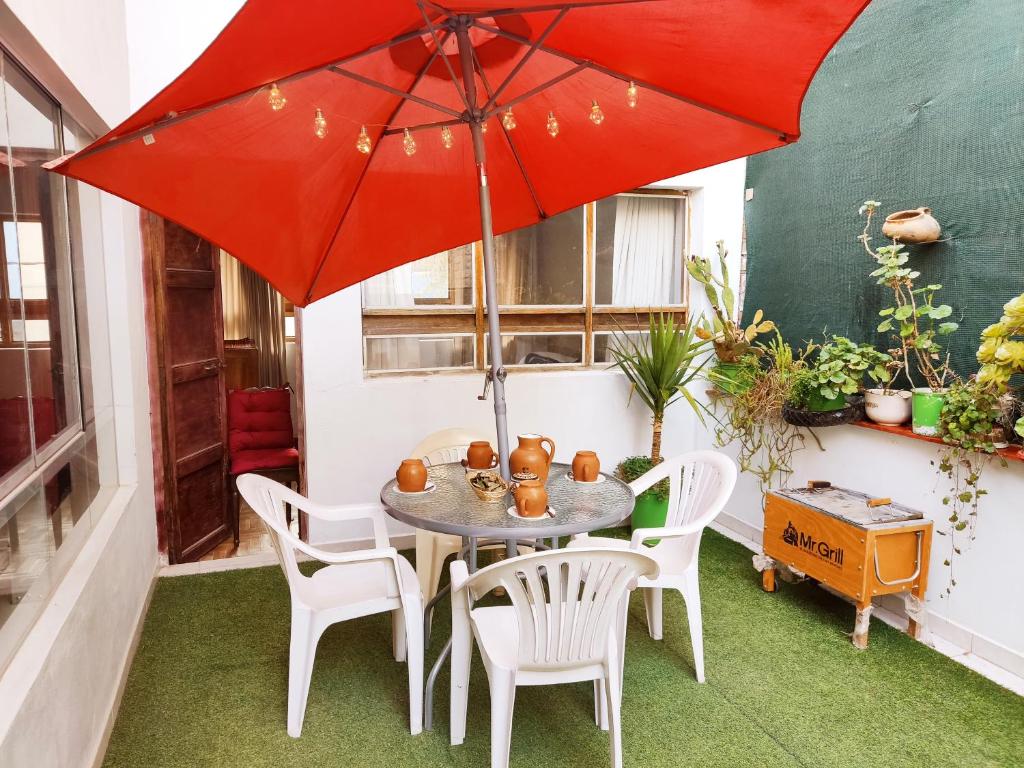 a patio with a table and chairs and a red umbrella at Samayuna Wasi , entire apartment Cusco in Cusco