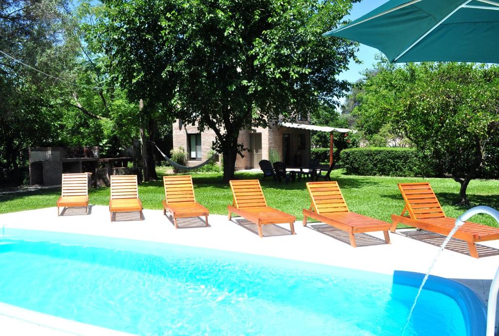 a group of chairs and an umbrella next to a pool at Los Olivos Loft in Rosario
