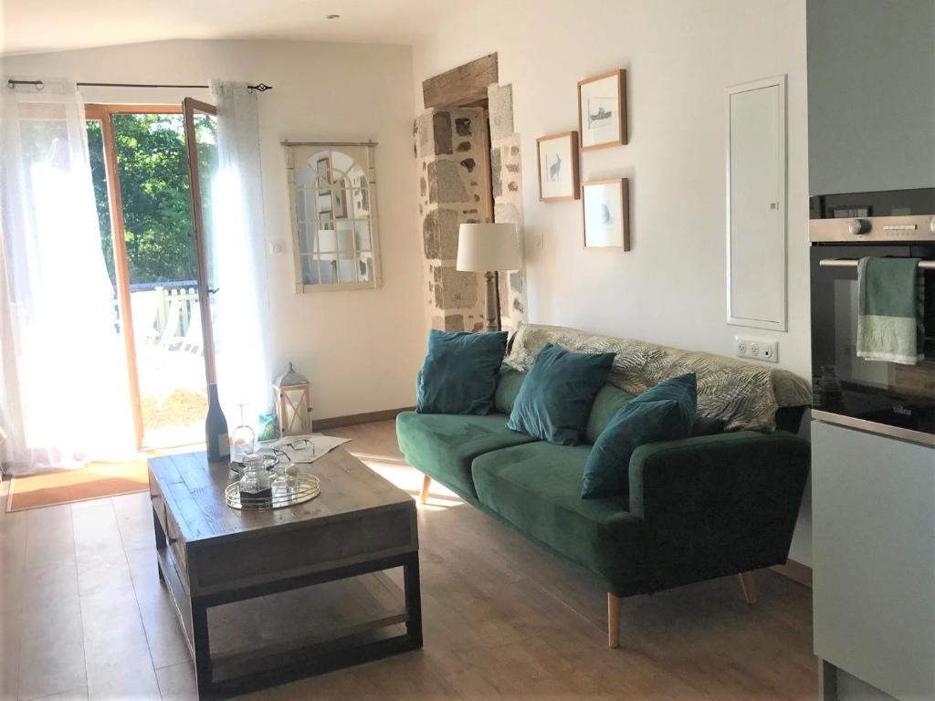 sala de estar con sofá verde y mesa de centro en La Petite Grange Gite, en Oradour-Fanais