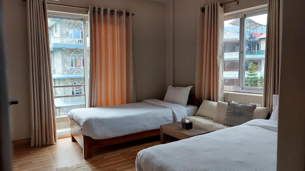 una camera d'albergo con due letti e un divano di Hotel Blossom a Pokhara
