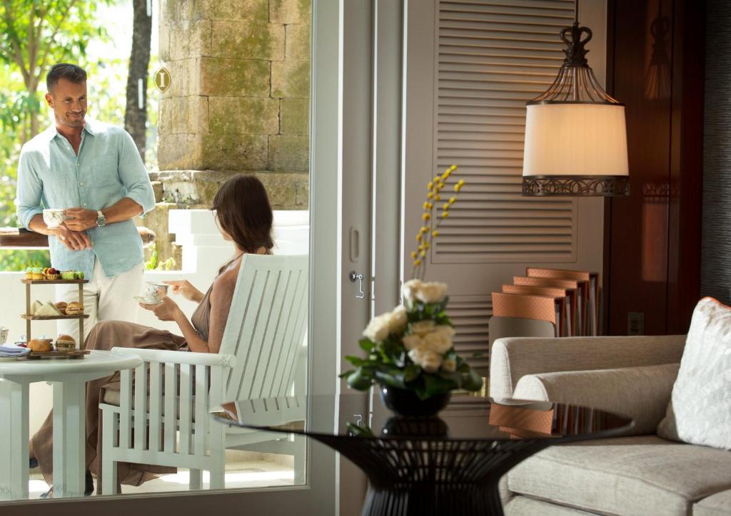 a man and a woman sitting in chairs in a living room at InterContinental Bali Resort by IHG in Jimbaran