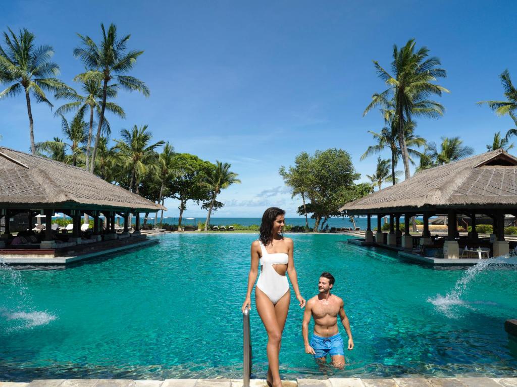 a woman in a bikini standing in the water at a resort at InterContinental Bali Resort, an IHG Hotel in Jimbaran