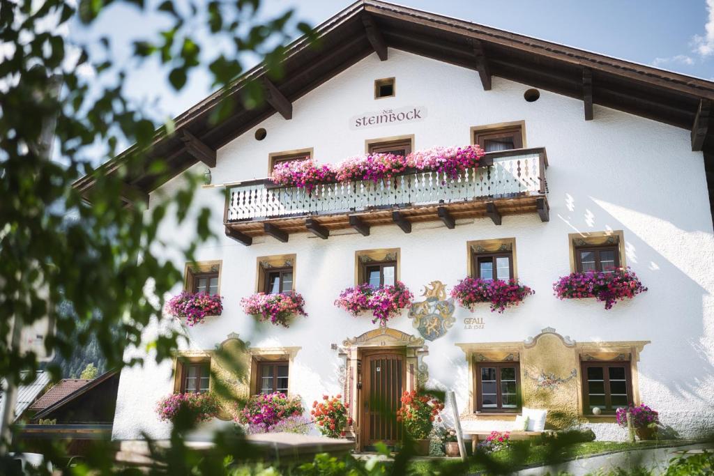 un edificio blanco con flores en los balcones en Pension der Steinbock - das 300 Jahre alte Bauernhaus - TIROL en Sankt Anton am Arlberg