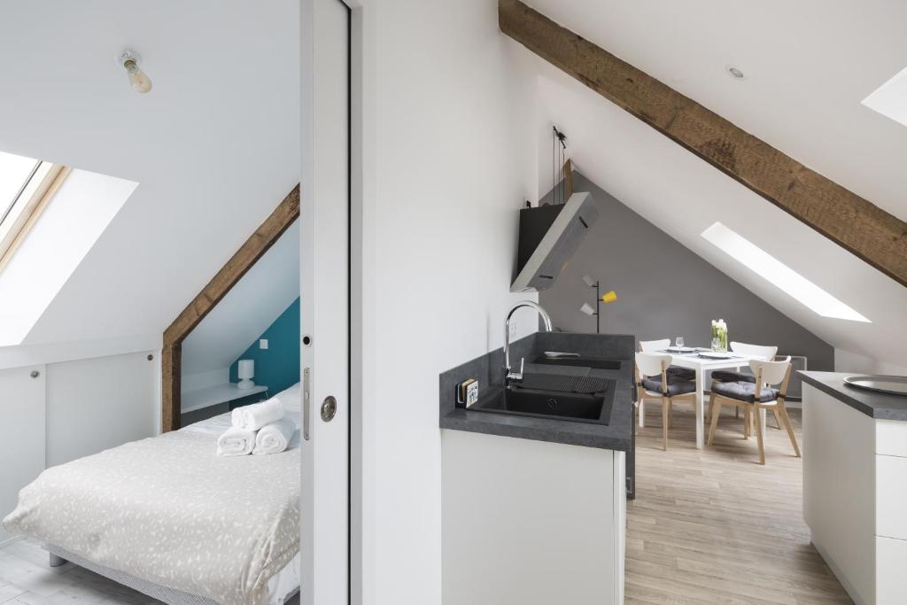 a bedroom with a bed and a kitchen with a sink at LE NOROIT - Cocon lumineux sur le Sillon in Saint Malo