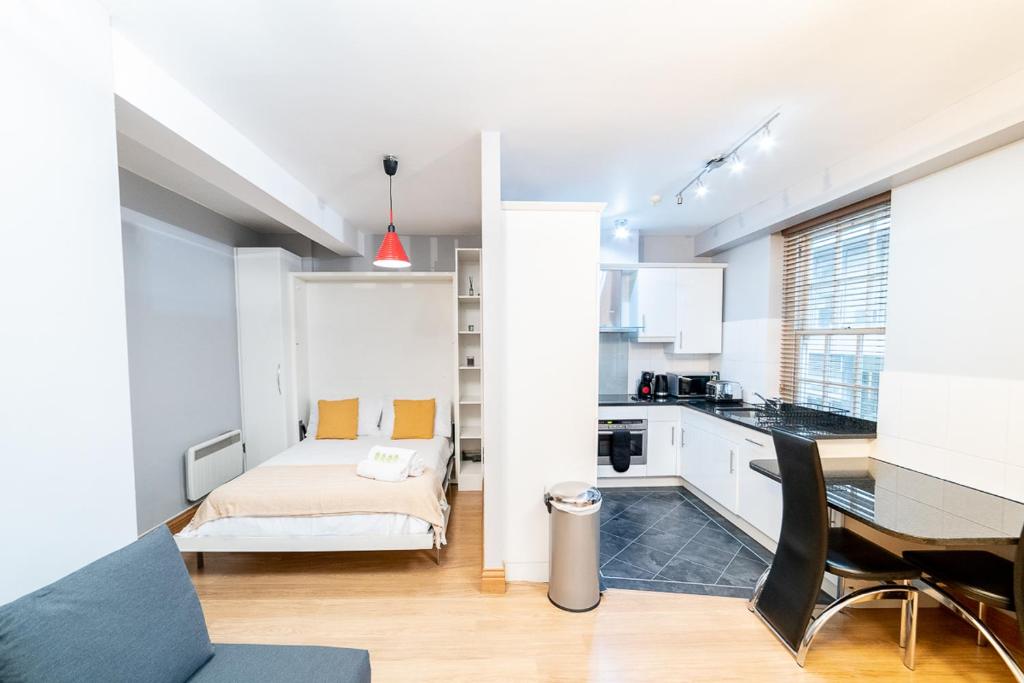 a living room with a bed and a desk in a room at (St' Paul Cathedral) London Studio Apartment in London