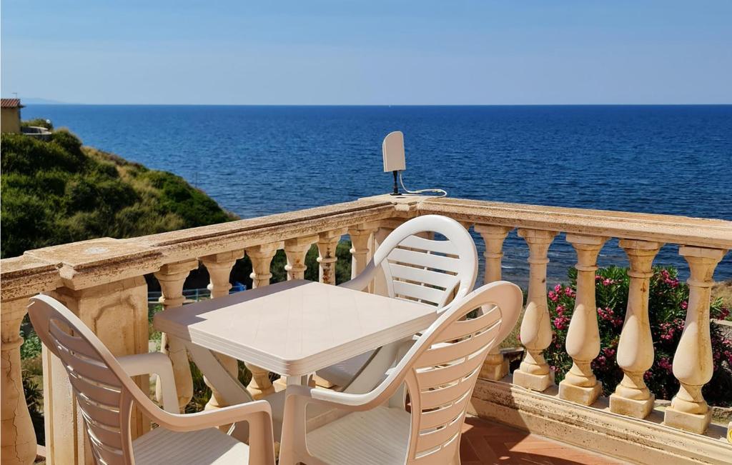 een tafel en stoelen op een balkon met uitzicht op de oceaan bij Cozy Apartment In La Ciaccia With Kitchen in Codaruina
